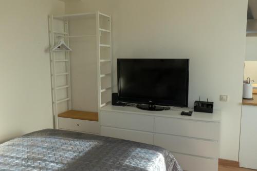 a bedroom with a flat screen tv on a dresser at Cozy Apartment at Central Market - Liepajas heart in Liepāja