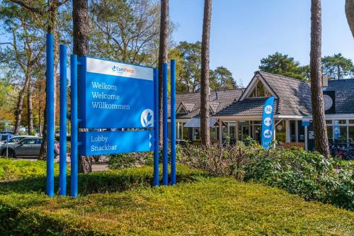 un cartel en el césped frente a un edificio en EuroParcs Beekbergen, en Beekbergen