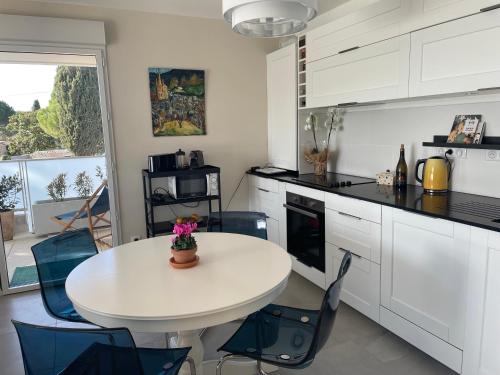 uma cozinha com uma mesa branca e cadeiras azuis em Superbe appartement T3 proche de la garrigue em Castries