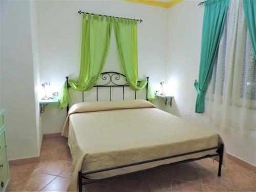 una camera da letto con letto e tende verdi di Residenza Su Portu a Orosei