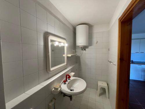 La salle de bains blanche est pourvue d'un lavabo et d'un miroir. dans l'établissement Appartamento vista mare a Tanca Manna - Cannigione, à Cannigione