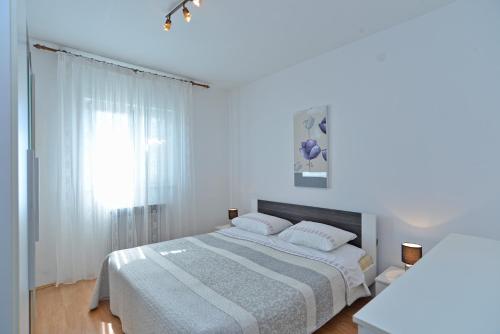 ein weißes Schlafzimmer mit einem Bett und einem Fenster in der Unterkunft Apartments Mira 615 in Rovinj