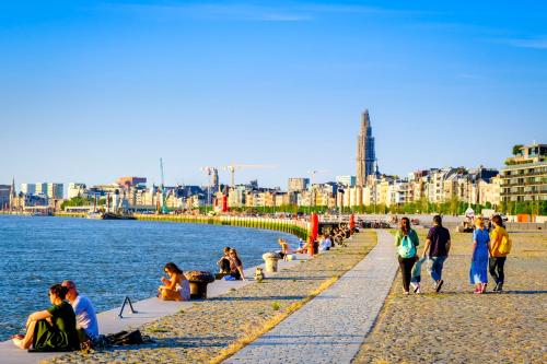a group of people walking on a sidewalk next to the water at ibis Antwerpen Centrum in Antwerp