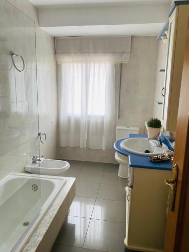ein Badezimmer mit Badewanne, Toilette und Waschbecken in der Unterkunft Combarro Suite in Combarro