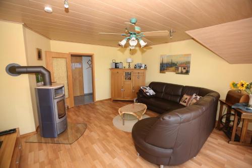 a living room with a leather couch and a fireplace at Ferienwohnung Maria Waldblick 95 qm, in Burtenbach