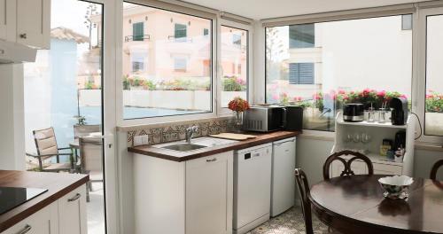 a kitchen with white cabinets and a table and windows at Villa da Praia in Sintra
