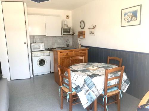 Il comprend une petite cuisine avec une table, des chaises et une cuisinière. dans l'établissement Carnac plage T2 avec terrasse Pour 4 personnes, à Carnac