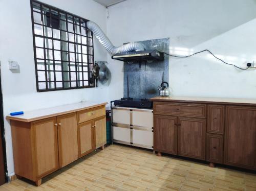 uma cozinha com armários de madeira e um fogão em D'Hiquapis Homestay em Seri Manjung