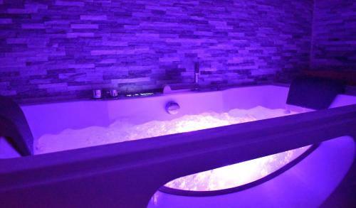 - une baignoire avec éclairage violet dans la chambre dans l'établissement Logis Manoir de Fourcy, à Corbehem