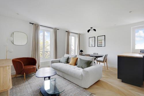 een witte woonkamer met een bank en een tafel bij Pick A Flat's Apartment on Place du Tertre in Parijs
