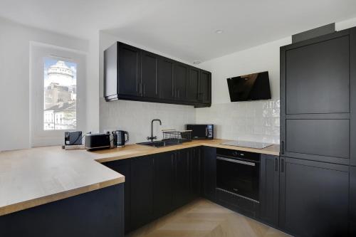 une grande cuisine avec des armoires noires et une fenêtre dans l'établissement Pick A Flat's Apartment on Place du Tertre, à Paris