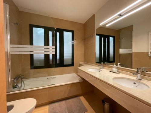 y baño con 2 lavabos, bañera y aseo. en Casadeluxe El Oasis en Fuente Alamo