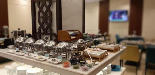 a buffet line with cups and dishes on a table at Three Points Al Salama in Jeddah