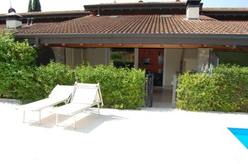 un par de bancos blancos sentados frente a una casa en Casa Vacanze "Il Porticciolo", en Manerba del Garda