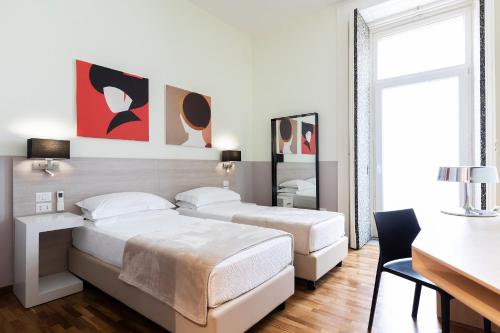 ナポリにあるB&B Starbienのベッドルーム1室(ベッド2台、デスク、テーブル付)