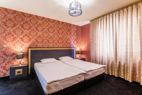 a bedroom with a large bed with red wallpaper at Hotel Elegance in Stara Zagora