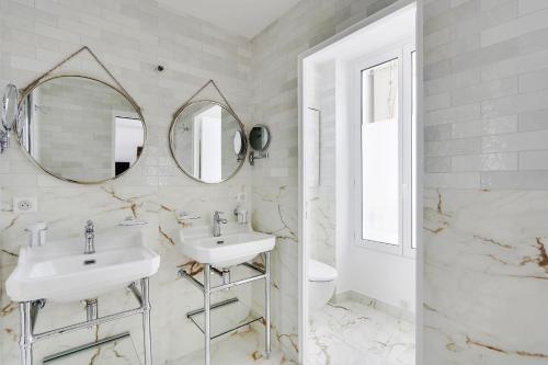 een witte badkamer met 2 wastafels en een spiegel bij Pick A Flat's Apartment on Place du Tertre in Parijs