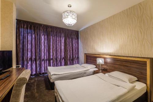 a bedroom with two beds and a desk and a window at Hotel Elegance in Stara Zagora