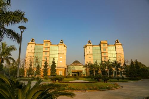 a large building with palm trees in front of it at Four Leaf Service Suites, Haridwar in Roorkee