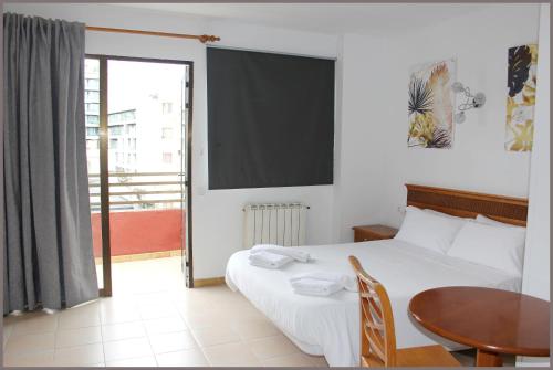 1 dormitorio con cama, mesa y ventana en Apartamentos Gomila Park en Palma de Mallorca