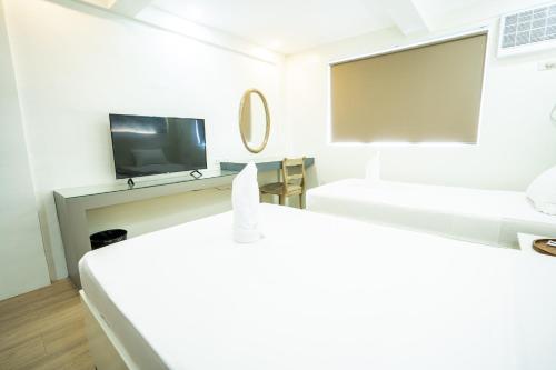 a room with two beds and a flat screen tv at The Garden Galleries Boutique Hotel in Pilar