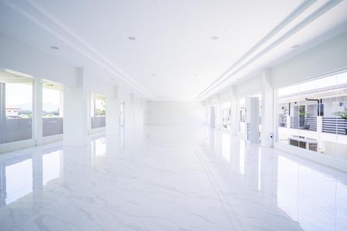 a white hallway of a building with white floors and windows at The Garden Galleries Boutique Hotel in Pilar