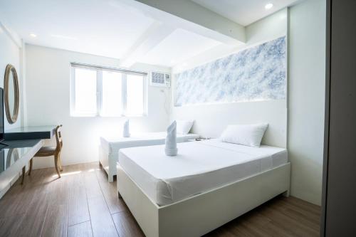 a white bedroom with a bed and a desk at The Garden Galleries Boutique Hotel in Pilar