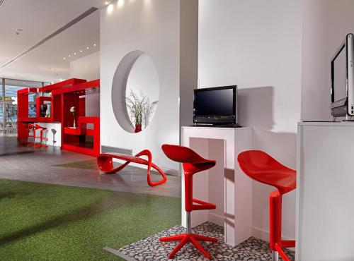 a living room with red chairs and a tv at Airotel Patras Smart Hotel in Patra