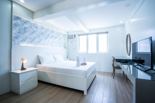 a white bedroom with a bed and a desk at The Garden Galleries Boutique Hotel in Pilar