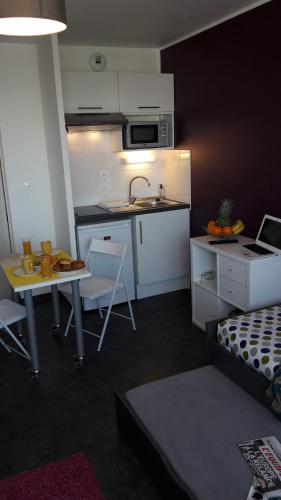 a room with a kitchen and a living room with a table at Résidence Nemea Caen Beaumois in Caen