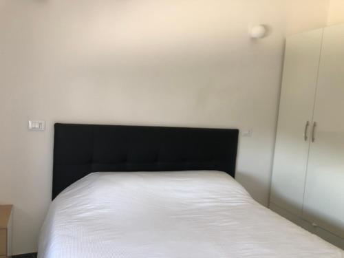 1 dormitorio con cama blanca y cabecero negro en La rocca en Caorso