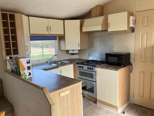 une petite cuisine avec une cuisinière et un micro-ondes dans l'établissement Mobilhome Coup de Coeur, à Sigean