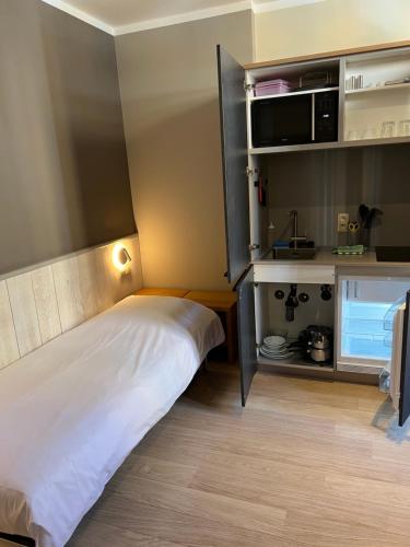 Una pequeña habitación con una cama y un microondas. en Boardhousing, en Lovaina