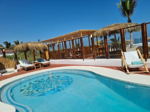 a swimming pool with two chairs and a umbrella at Maracol Bungalows Vichayito in Vichayito