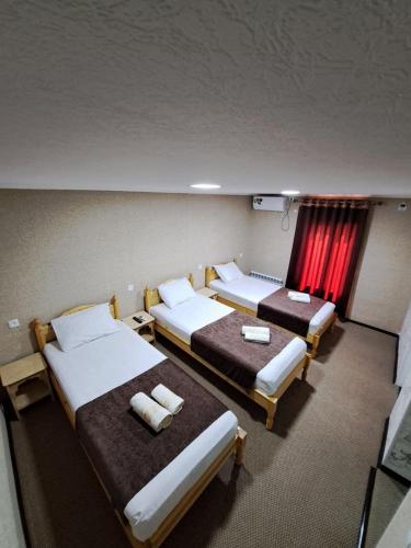 a room with three beds and a red curtain at Bukhara Hotel Alikhan in Bukhara