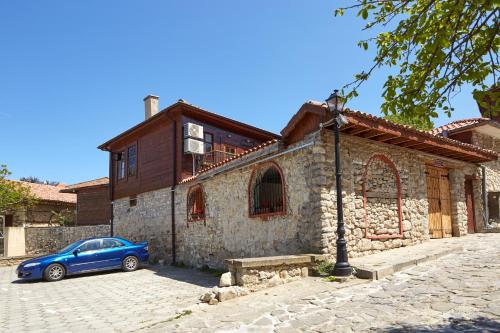 a blue car parked in front of a stone building at ВИЛА ТЪРТЕФФ in Nesebar
