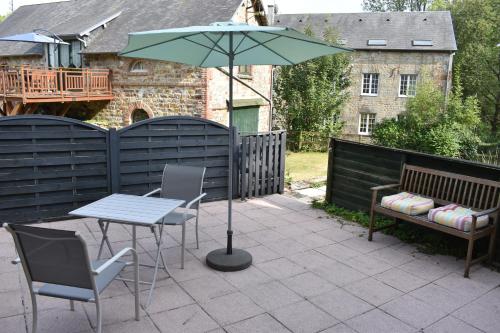 a patio with a table and chairs and an umbrella at Gites in Le Neufbourg -Mortain in Le Neufbourg