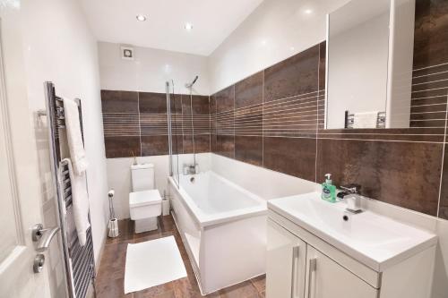 W białej łazience znajduje się umywalka i lustro. w obiekcie Modern city centre flat with free parking w mieście Leeds