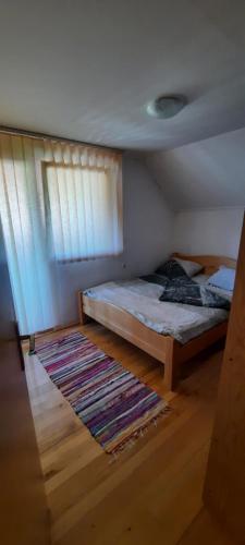 a bedroom with a bed and a window and a rug at Smjestaj na selu Stankovic - Pliva in Šipovo