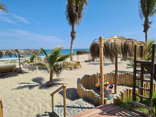 a beach with a fence and palm trees and the ocean at Maracol Bungalows Vichayito in Vichayito