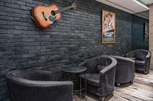 a guitar hanging on a brick wall with two chairs at Taiwan Youth Hostel & Capsule Hotel in Taipei