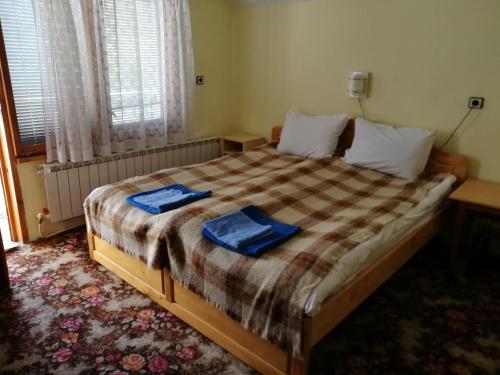 - une chambre avec un grand lit et des serviettes bleues dans l'établissement Самостоятелни стаи в къща за гости Балкан, à Ribarica