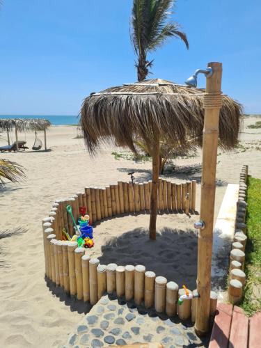 a beach with an umbrella on the beach at Maracol Bungalows Vichayito in Vichayito