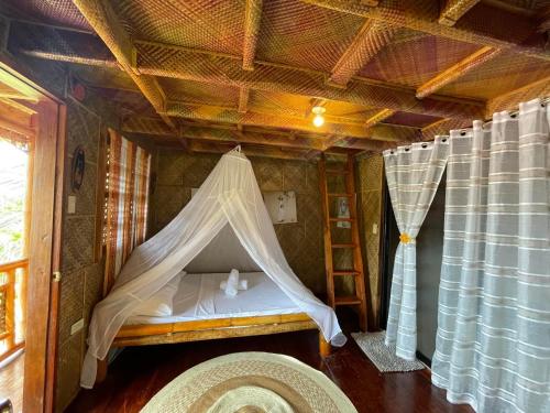 a bedroom with a bed with a mosquito net at Camiguin Blue Lagoon Cottages in Mahinog