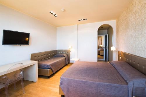 a hotel room with two beds and a flat screen tv at Hotel San Francisco in Viareggio