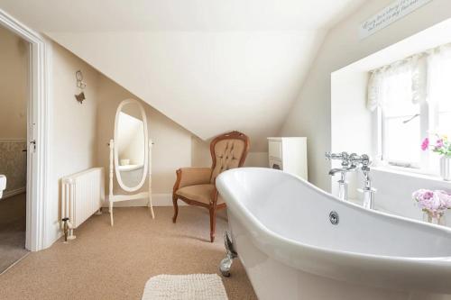 a white bathroom with a tub and a chair at St Anne's House in Plymouth