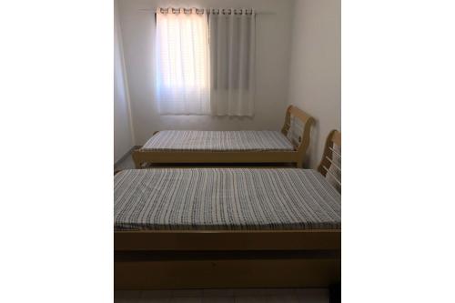 Un dormitorio con dos camas y una ventana en T004 - Apto na Tupi com sacada, garagem e ótima localização, en Samaritá