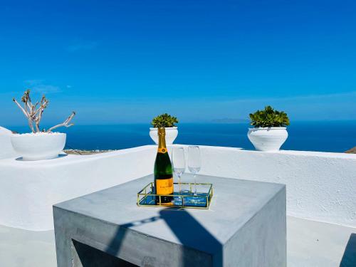 a bottle of wine sitting on a table with glasses at Amphora Villas Santorini Pyrgos in Pirgos