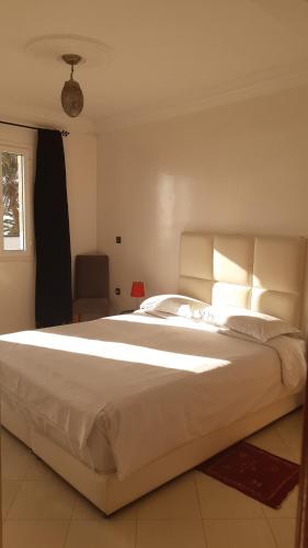 a large white bed in a room with a window at Résidence Louzani in Essaouira