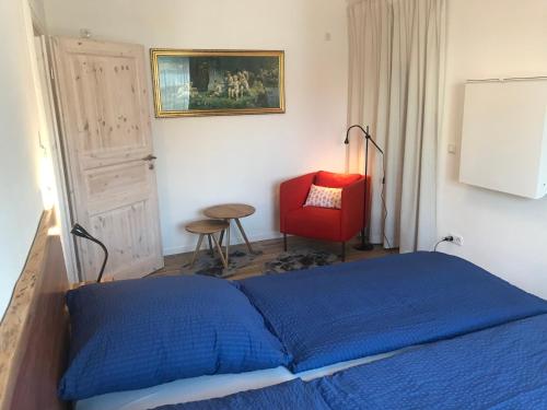 um quarto com uma cama azul e uma cadeira vermelha em Alte Post Altwahnsdorf em Radebeul